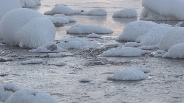 冬天有霜雾的河流。冷水中的岩石被雪覆盖着视频素材