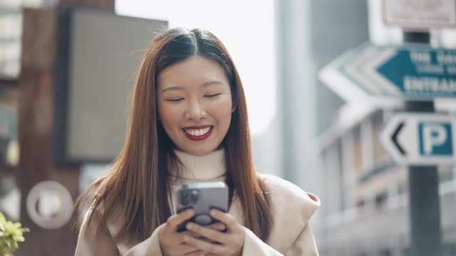 亚洲女人走路和使用智能手机视频素材