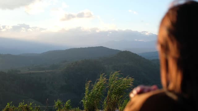 模糊的后视图，一个女性旅行者在看一个美丽的绿色山景视频素材