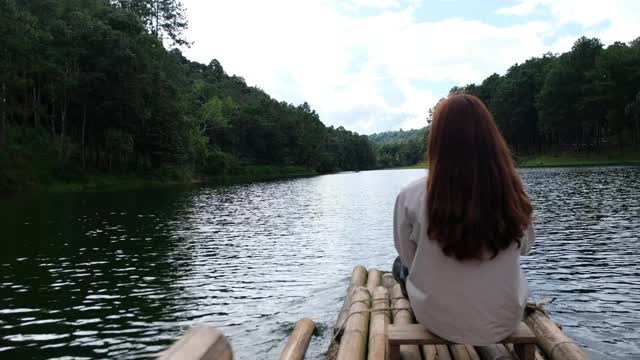 后视图的女性旅行者坐在和骑竹筏在湖中视频素材