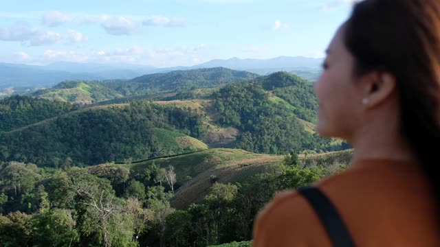 模糊的女旅人看着美丽的绿色山景视频素材