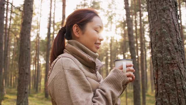 亚洲年轻女子在森林里喝热茶视频素材