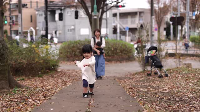 快乐的小女孩在公园里散步，妈妈正看着她视频素材