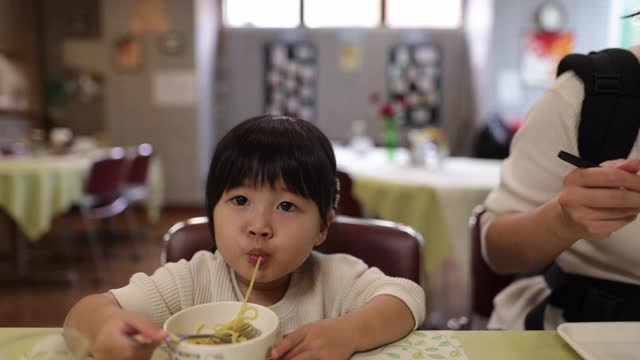 年轻的母亲和她的小女儿午餐吃拉面视频素材