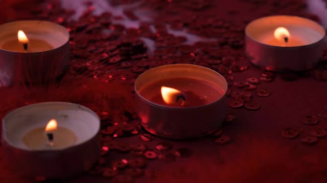 特写燃烧的茶灯蜡烛聚集在一起的红色背景。浪漫的氛围与香茗香薰蜡烛。情人节的背景视频素材