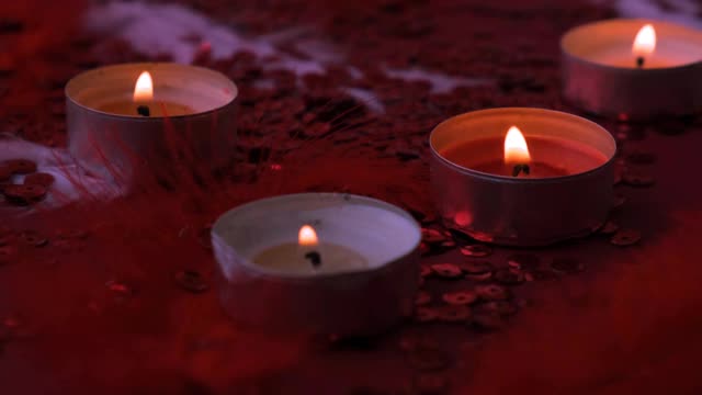 特写燃烧的茶灯蜡烛聚集在一起的红色背景。浪漫的氛围与香茗香薰蜡烛。情人节的背景视频素材