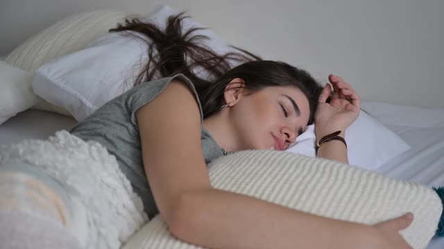 平静的年轻女子睡在舒适舒适的白色床上，柔软的枕头，安静安详的女孩躺着睡觉，享受健康良好的睡眠小睡在早上在家视频素材