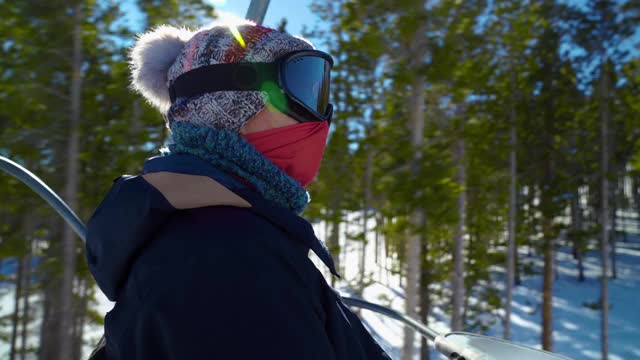 带面罩的女子滑雪者在高山度假村的滑雪缆车上站起来视频素材