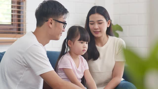 快乐的亚洲家庭爸爸，妈妈和女儿拥抱亲吻脸颊在家里祝贺生日。视频素材