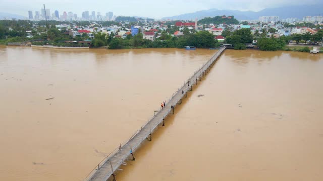 空中慢镜头拍摄的木桥横跨亚洲的河流和摩托车骑在上面。危险交通建设概念视频素材