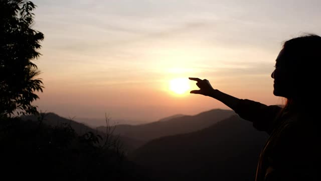 早晨在山顶上，一位女旅行者正在伸手去抓太阳视频素材