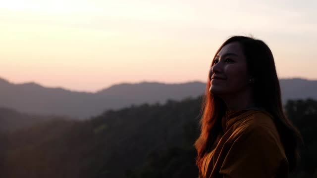 一个女性旅行者坐在山顶上的特写，在早上看日出视频素材