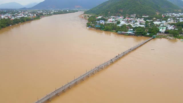 空中慢镜头拍摄的木桥横跨亚洲的河流和摩托车骑在上面。危险交通建设概念视频素材