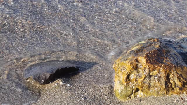 海浪的近景。海岸上有粗糙的沙子和小卵石。视频素材