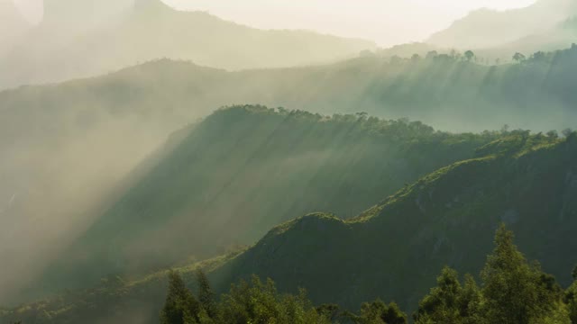 早晨的太阳在薄雾，雾山景观创造美丽的光线通过山谷-时间流逝视频下载