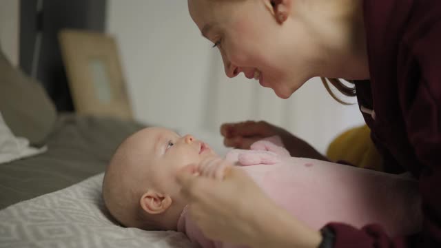 年轻漂亮的妈妈带着孩子。新生儿和他的妈妈。母亲朝她的孩子微笑。快乐的年轻女人和她的孩子。4 k的视频视频素材