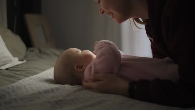 年轻漂亮的妈妈带着孩子。新生儿和他的妈妈。母亲朝她的孩子微笑。快乐的年轻女人和她的孩子。4 k的视频视频下载