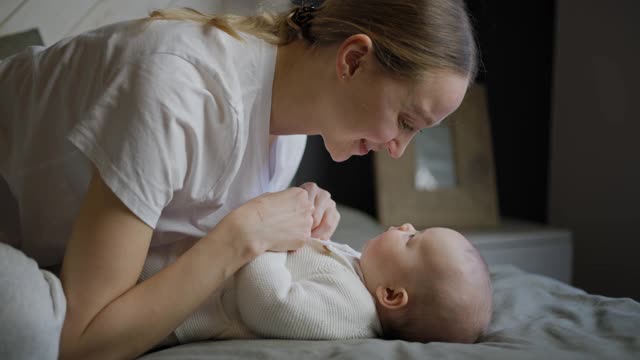 年轻漂亮的妈妈带着孩子。新生儿和他的妈妈。母亲朝她的孩子微笑。快乐的年轻女人和她的孩子。4 k的视频视频素材