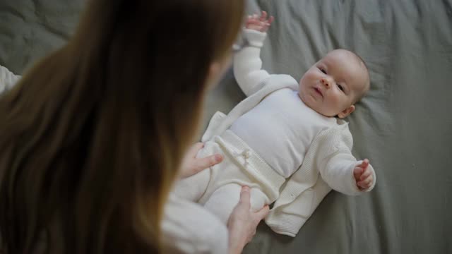 快乐的女人看着她的孩子笑了。漂亮的宝宝朝妈妈笑。母亲和她自己的孩子视频素材