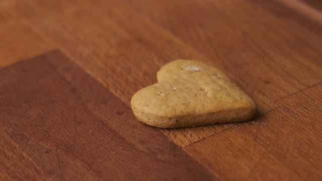 在木桌上用粉红色的釉面装饰情人节的姜饼或饼干视频素材