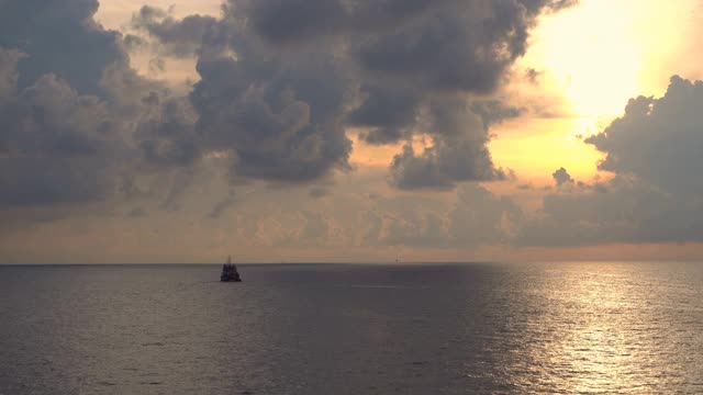 日落大海。橘红色日出戏剧性的天空和云与船的剪影在地平线上。视频素材