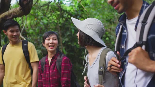 一群年轻的亚洲男人和女人朋友一起在森林里旅行。他们在大自然中感到清新和放松，看着并指向风景，然后继续散步，快乐和乐趣。视频素材