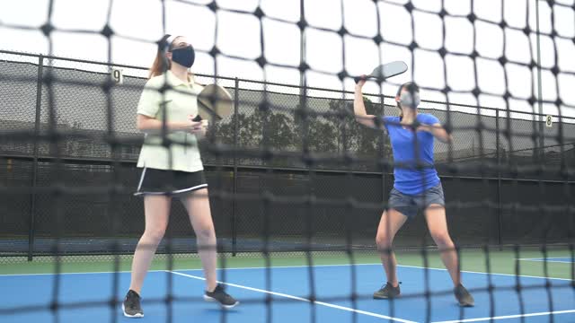 两个年轻女子在玩pickleball，戴着面具视频素材