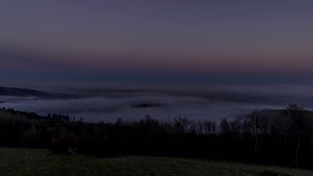 在Valasske Mezirici的Beskydy地区，一个沐浴在浓雾和云中的城市的延时日出移动到一个山谷周围的景观。视频素材