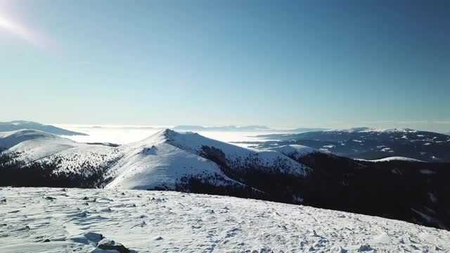 在Amerinkogel地区，一架无人机拍摄到被雪覆盖的阿尔卑斯山。山谷里有浓雾。山坡上茂密的森林。奥地利阿尔卑斯山的冬天。无尽的山脉。阳光明媚的一天。视频素材