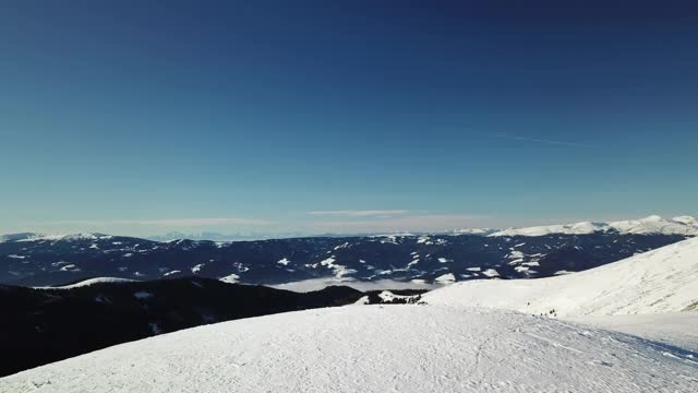 在Amerinkogel地区，一架无人机拍摄到被雪覆盖的阿尔卑斯山。山谷里有浓雾。山坡上茂密的森林。奥地利阿尔卑斯山的冬天。无尽的山脉。阳光明媚的一天。视频素材