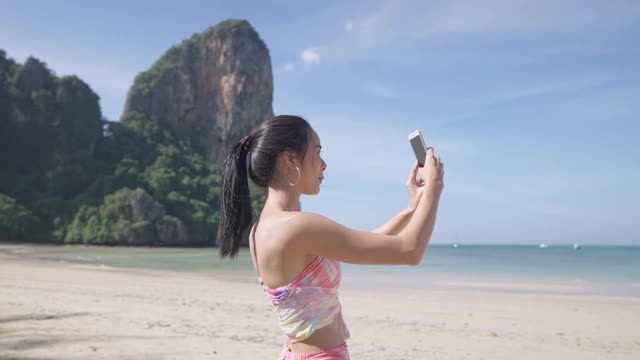 年轻美丽的亚洲女人通过智能手机视频呼叫朋友在热带岛屿海滩放松之旅，视频素材