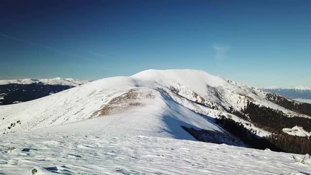 在Amerinkogel地区，一架无人机拍摄到被雪覆盖的阿尔卑斯山。山谷里有浓雾。山坡上茂密的森林。奥地利阿尔卑斯山的冬天。无尽的山脉。阳光明媚的一天。视频素材