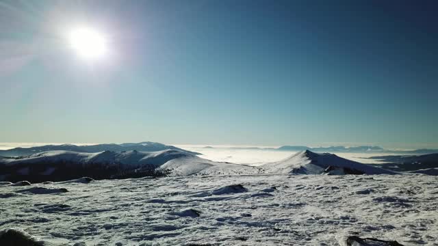 在Amerinkogel地区，一架无人机拍摄到被雪覆盖的阿尔卑斯山。山谷里有浓雾。山坡上茂密的森林。奥地利阿尔卑斯山的冬天。无尽的山脉。阳光明媚的一天。视频素材