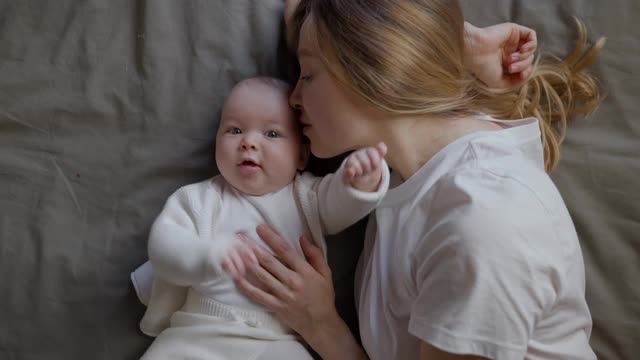 妈妈和她的孩子躺着，从上面看镜头。美丽的年轻女人和她的孩子。母亲和女儿。幸福的家庭视频素材