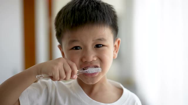 一个亚洲小孩在浴室里刷牙。日常健康和牙科护理的概念视频素材