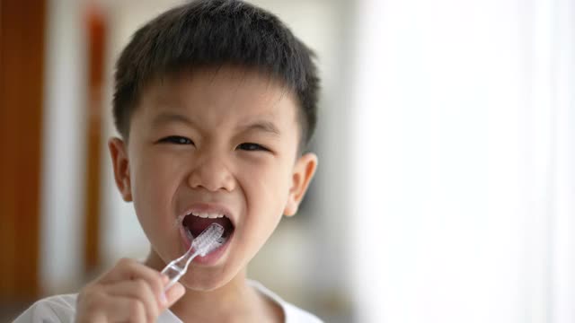 一个亚洲小孩在浴室里刷牙。日常健康和牙科护理的概念视频素材