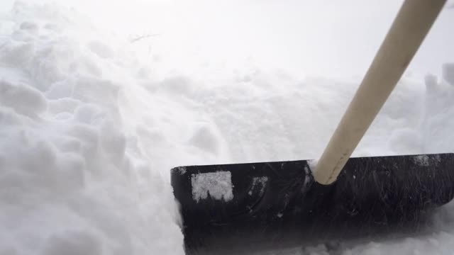 铲子的特写镜头，一个男人用铲子在他的院子里清理雪。俄罗斯的冬天把院子覆盖上了雪视频素材