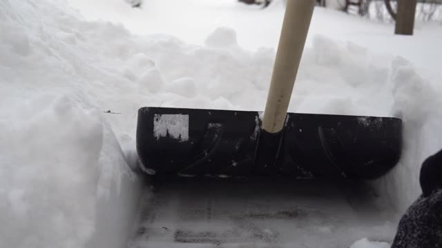 铲子的特写镜头，一个男人用铲子在他的院子里清理雪。俄罗斯的冬天把院子覆盖上了雪视频素材