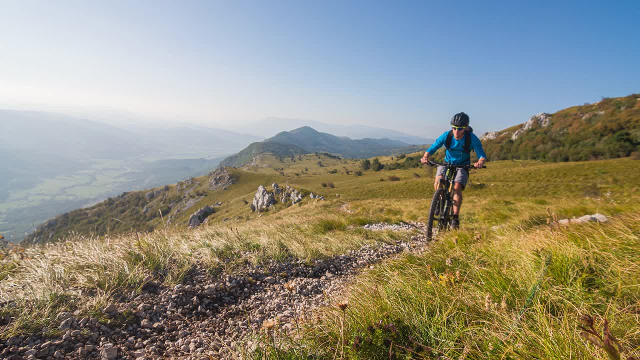 男运动员山地自行车在山上的草地景观视频素材