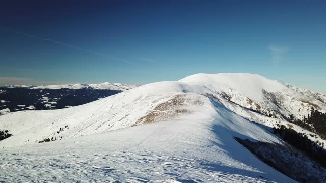 在Amerinkogel地区，一架无人机拍摄到被雪覆盖的阿尔卑斯山。山谷里有浓雾。山坡上茂密的森林。奥地利阿尔卑斯山的冬天。无尽的山脉。阳光明媚的一天。视频素材