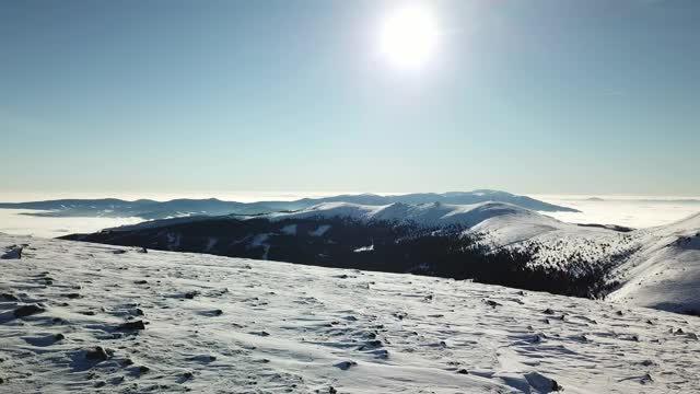 无人机拍摄到一对夫妇穿着雪地鞋徒步前往Amerinkogel峰。奥地利阿尔卑斯山的冬天。无尽的山脉，覆盖着粉状的雪。山谷里有浓雾。户外活动视频素材