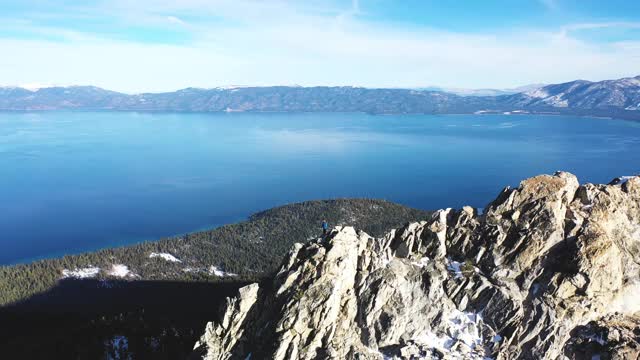 积雪覆盖的山顶W/湖无人机盘旋视频素材