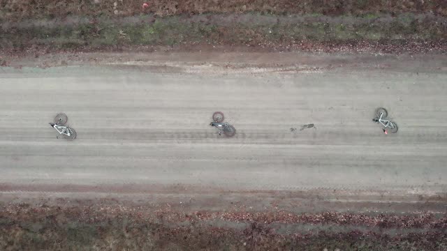 无人机正在飞越三辆碎石自行车躺在空旷肮脏的森林道路上。骑自行车的积极冒险视频素材