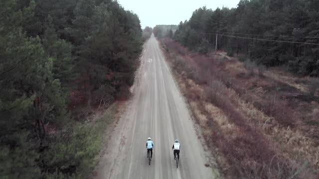 两名骑自行车的人在空旷的森林道路上骑着沙砾自行车。活跃的游客正在探索新地区的道路biсycles视频素材