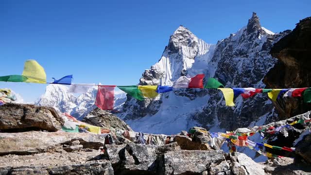 彩色的佛教经幡在强风中和平地飘扬在莲若拉山口，喜马拉雅山，尼泊尔，以冰雪覆盖的山脉为背景。视频素材