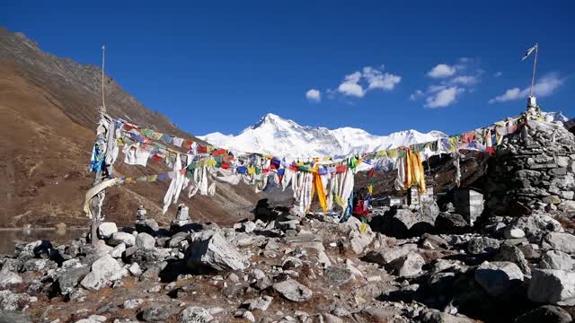 在尼泊尔的喜马拉雅山脉中，有雄伟的雪山卓奥友山，在Gokyo第三湖的岸边，一堆五颜六色的佛教经幡随风飘扬。视频素材