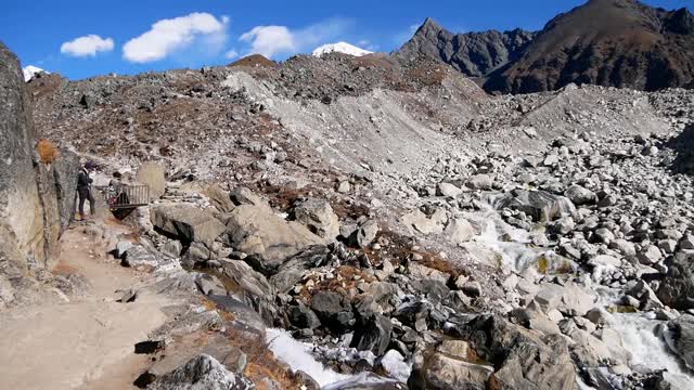 徒步旅行的徒步旅行者在喜马拉雅山附近的Gokyo，昆布Ngozumpa冰川的岩石冰碛之间观看野生山涧溪流和流动的水。视频素材