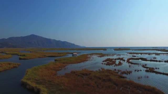 游船鸟瞰图。蜿蜒的蓝色河流和小镇。山所包围了。无人驾驶飞机。视频素材