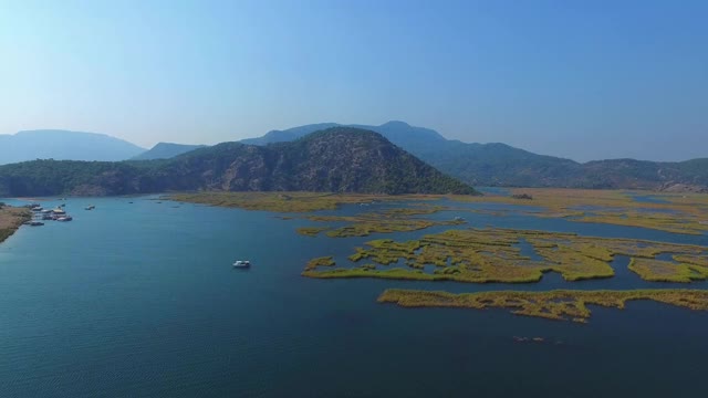 美丽的鸟瞰图芦苇在蓝色的水。山所包围了。船之旅。Iztuzu。无人驾驶飞机。视频素材