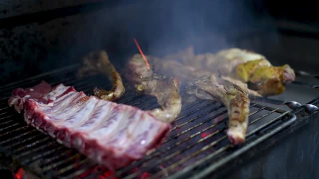 肉在炭火上烤。烧烤肋骨。将牛肉、羊肉、猪肉、鸡肉等多汁的肉类放在明火上，自然熏制。烹饪过程。视频素材